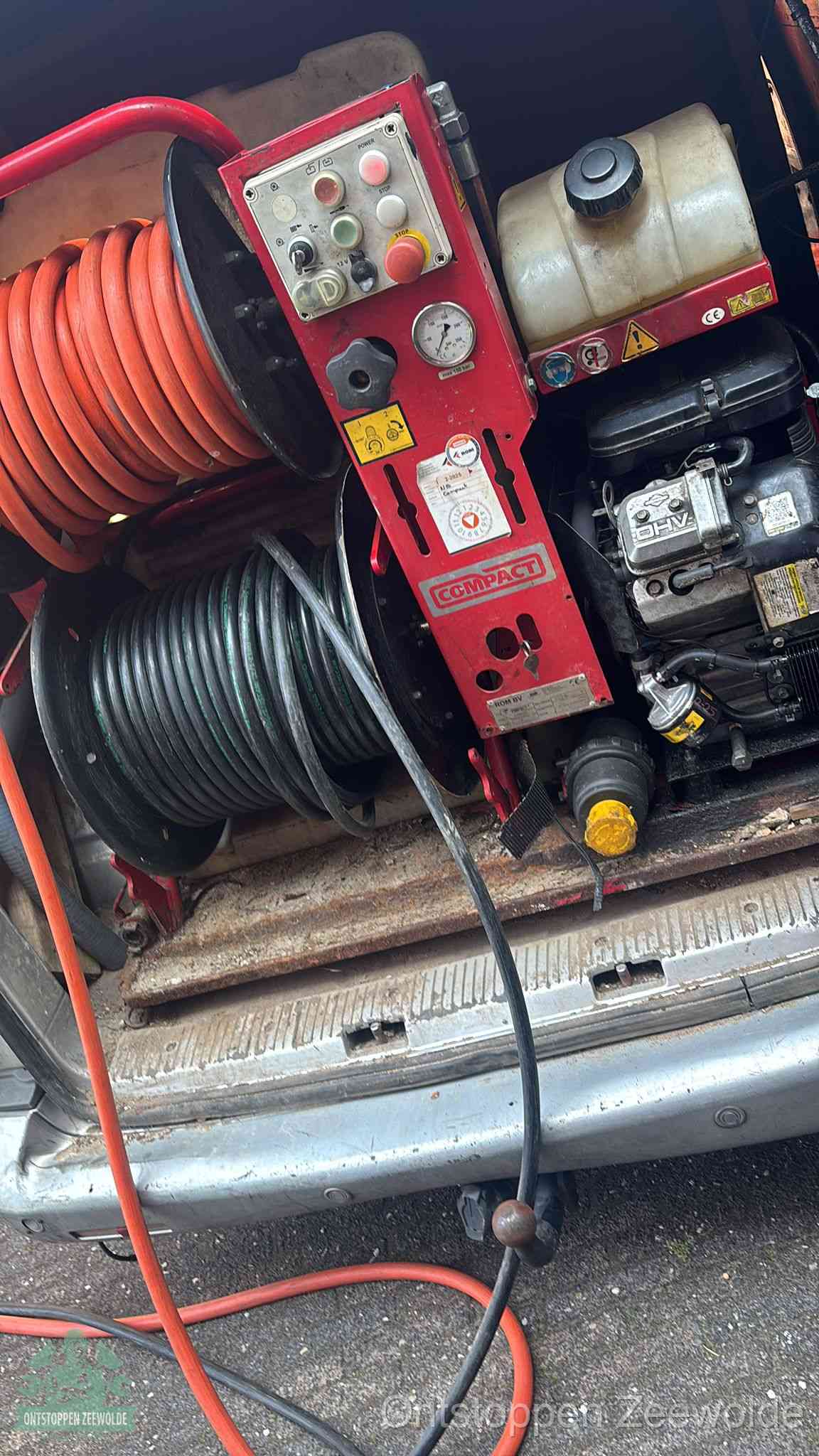 Een rood hogedruk-rioolreinigingstoestel met slangen in de laadbak van de bedrijfsbus, apparatuur voor een hardnekkige wc-verstopping in Zeewolde