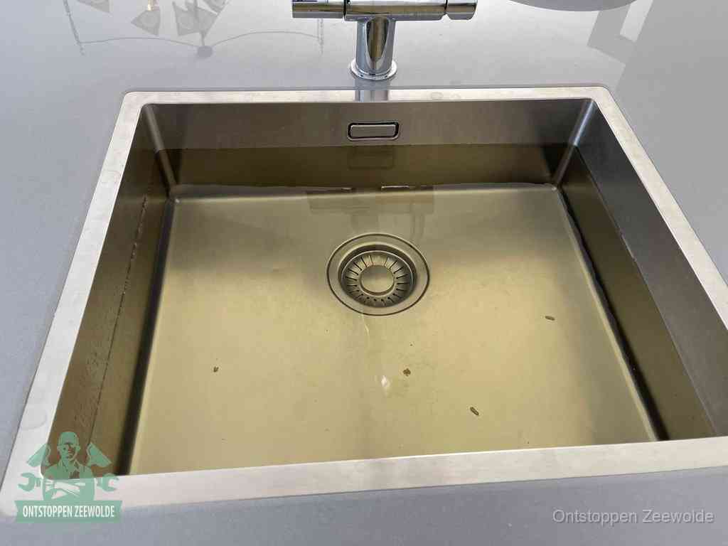 Stilstaand water in een rvs spoelbak dat niet wegloopt, een duidelijk signaal van een gootsteenverstopping in Zeewolde