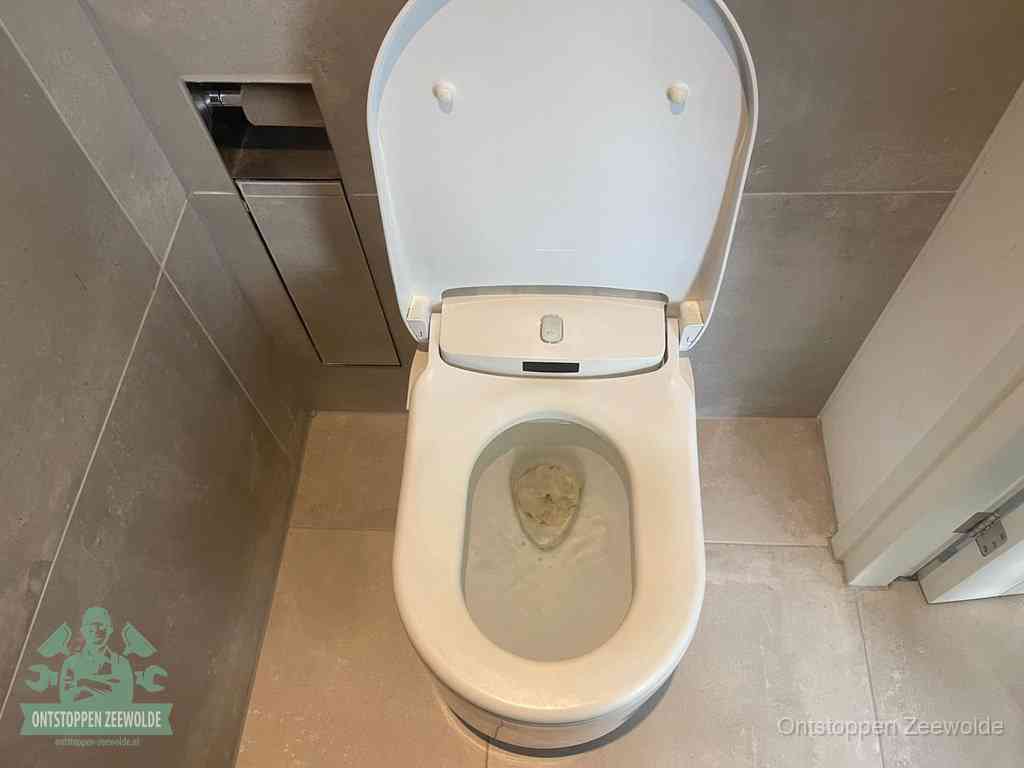 Een wit hangtoilet waarin een prop wc-papier op het water blijft drijven, een duidelijk signaal van een verstopte wc in Zeewolde