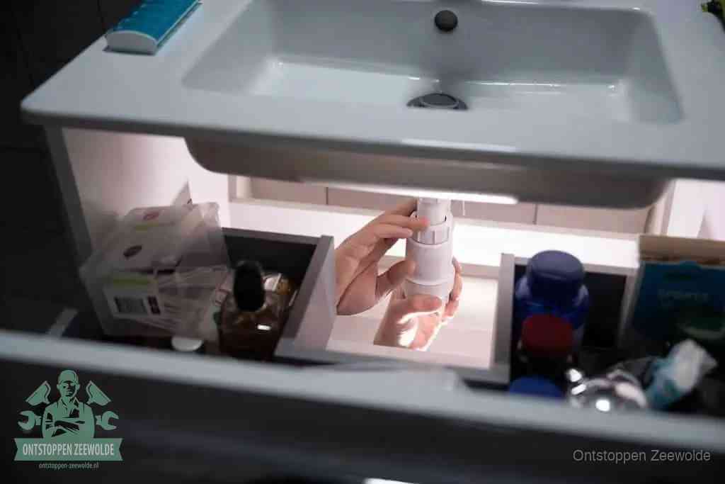 Een pompfles met zeep boven een wastafel in de toiletruimte, de warm water en afwasmiddel-methode om de wc te ontstoppen in Zeewolde