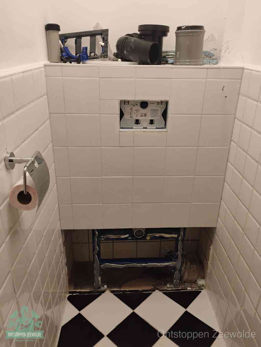 Een toiletruimte waar het hangtoilet en de inbouwreservoir-onderdelen zijn vrijgelegd voor onderhoud, periodiek nazicht voorkomt een wc-verstopping in Zeewolde