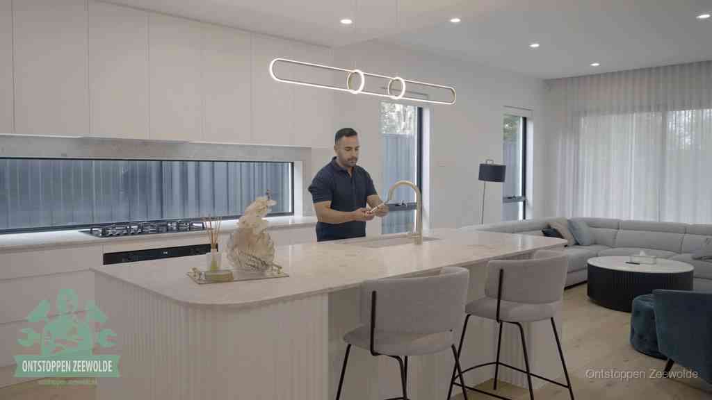 Een bewoner bij de keukenspoelbak die zelf aan de slag gaat met een verstopte gootsteen in Zeewolde